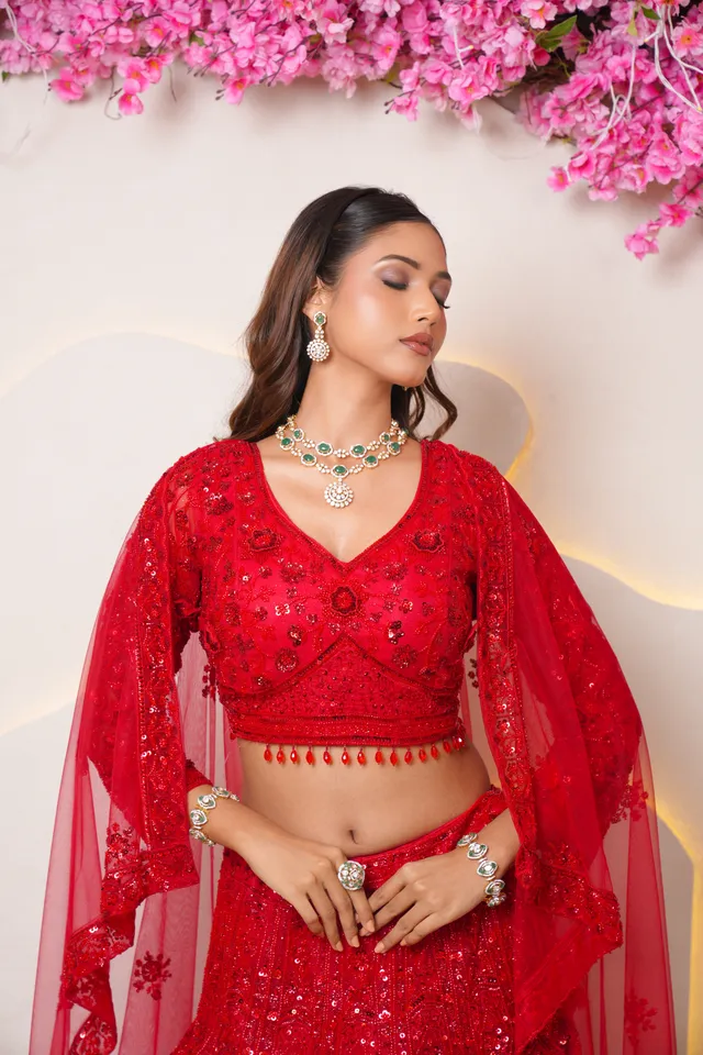Opulent traditional Indian bride in crimson lehenga, heavy gold jewellery and royal matha patti